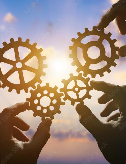 Hands holding cogs in front of a bright sun