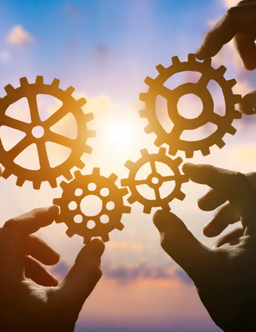 Hands holding cogs in front of a bright sun