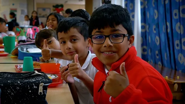 School children giving the thumbs up to their bean-based school dinners