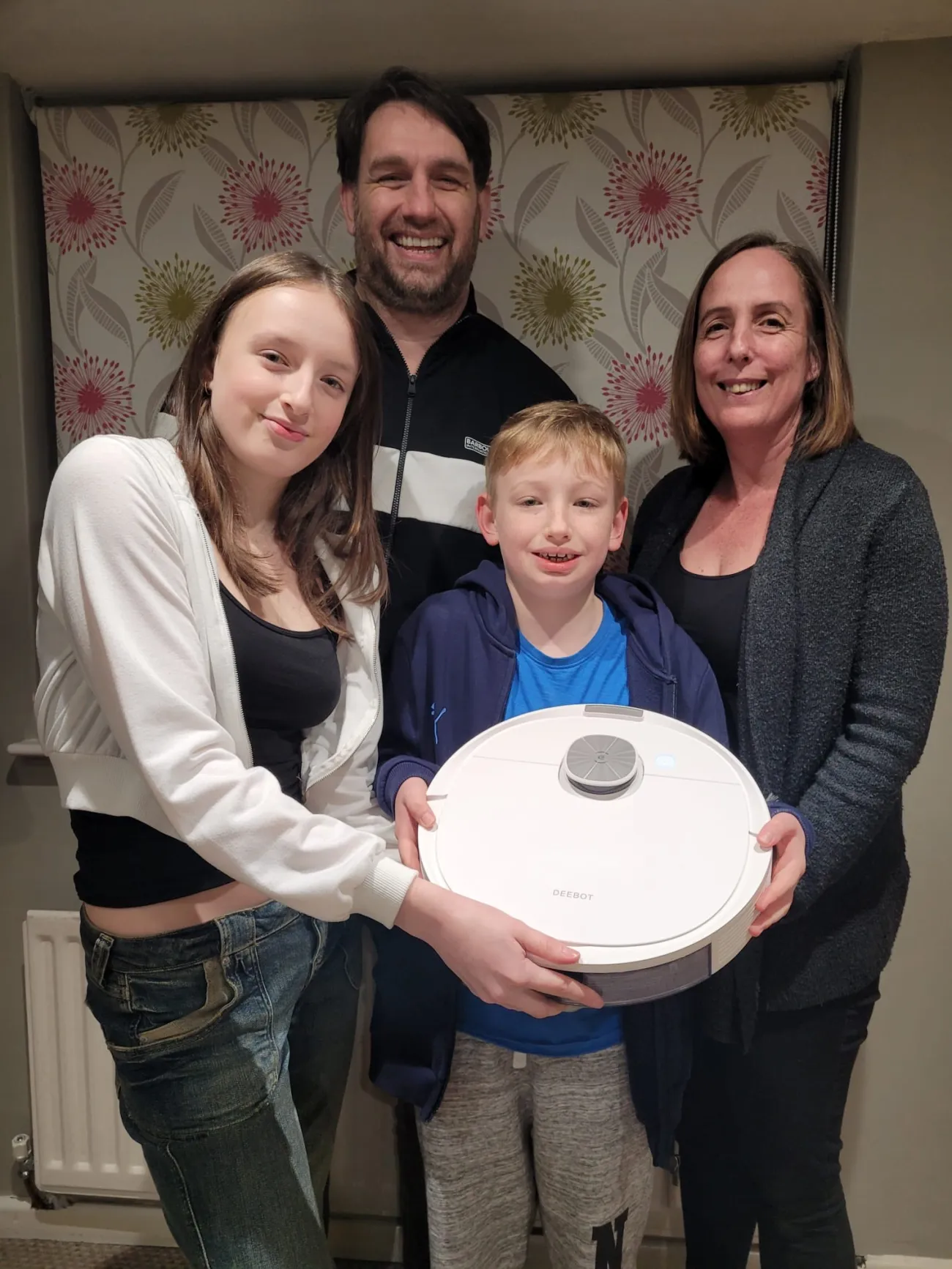 Parents and two children holding robot vacuum