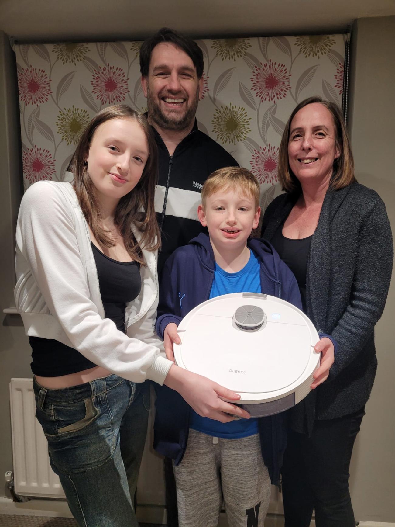 Parents and two children holding robot vacuum