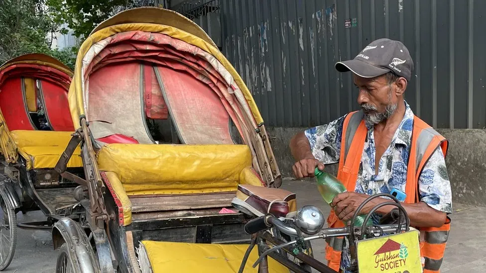 A Bangladeshi man with his rickshaw holding a bottle of water