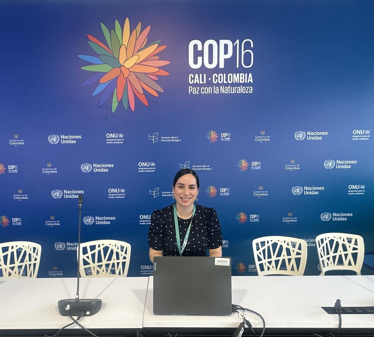 Paola Fajardo smiling in front of COP16 logo