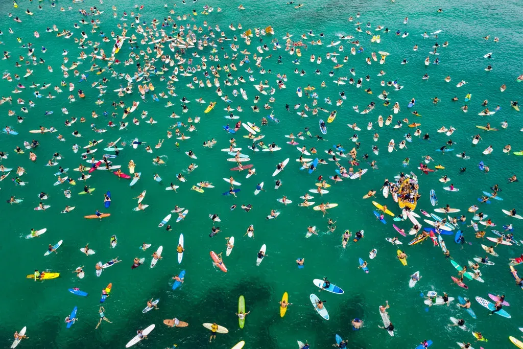 Aerial view of a surfers mass peaceful protest, surfers floating on surfboards on the ocean, a protest against an offshore oil drilling application