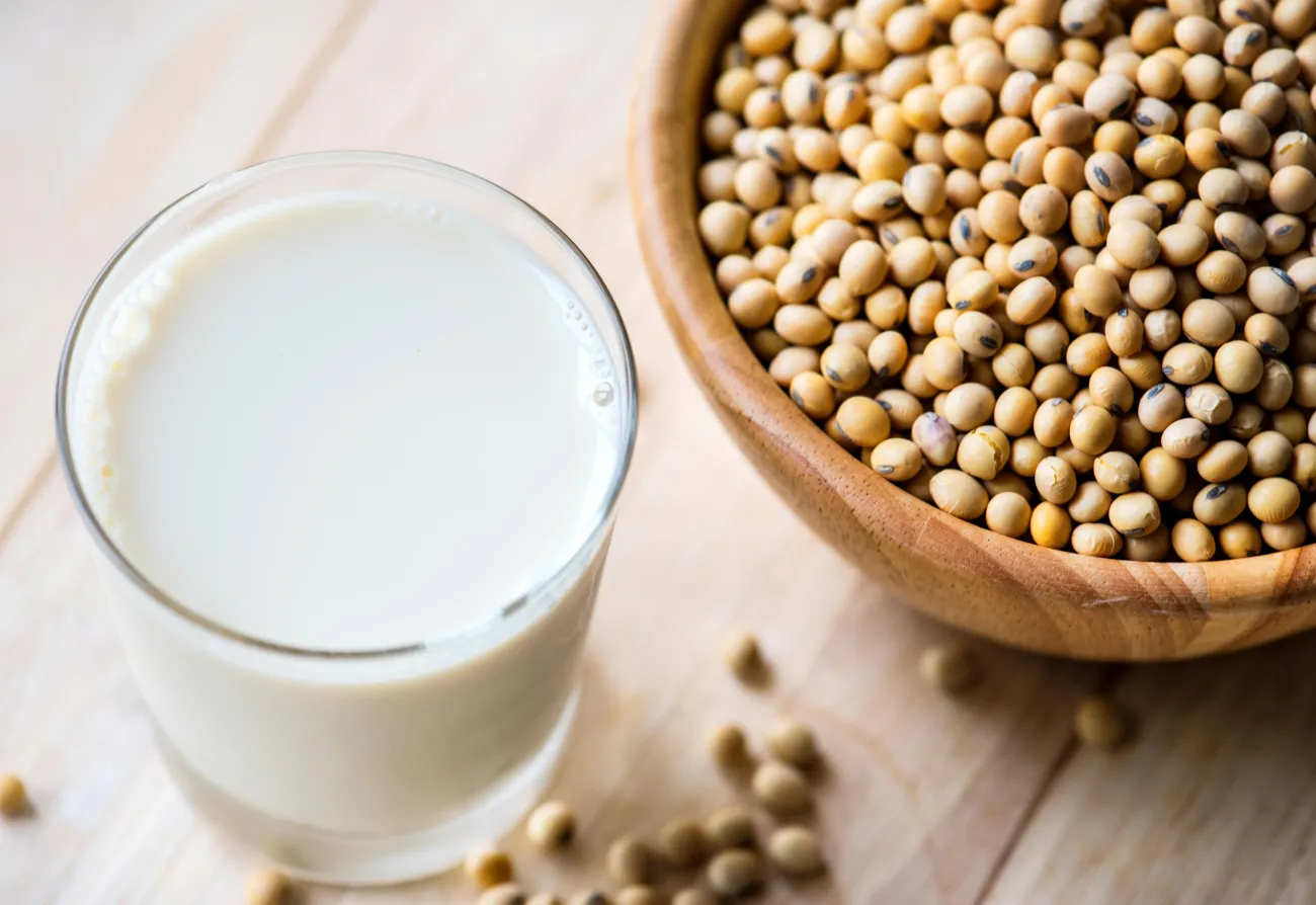 Glass of milk next to bowl of legumes
