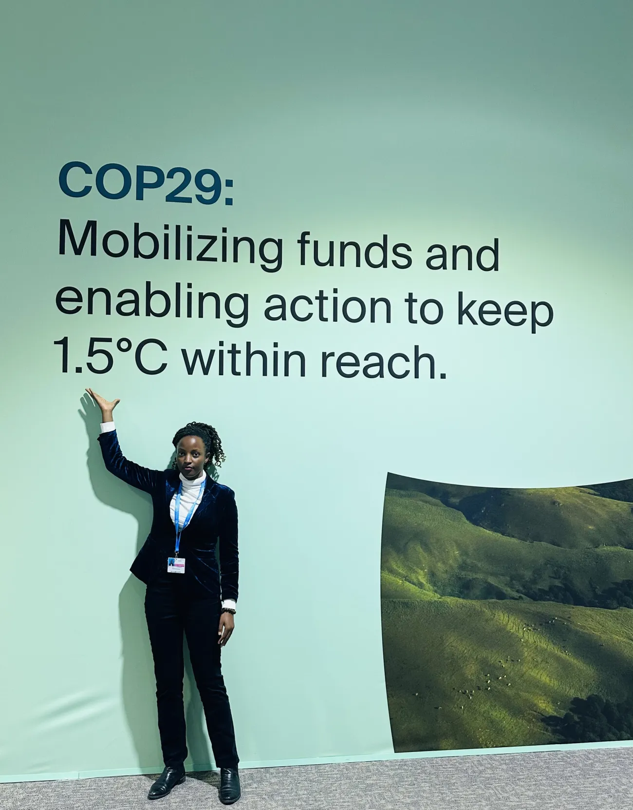 Rose Kobusinge standing below a COP29 wall banner
