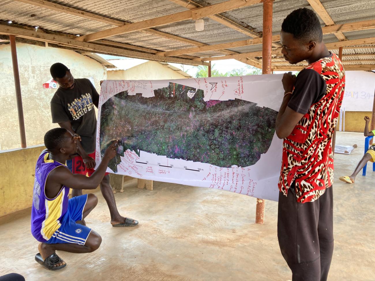 Three men holding a banner showing the mapping of their dronescape in Nsene, Central Region, Ghana