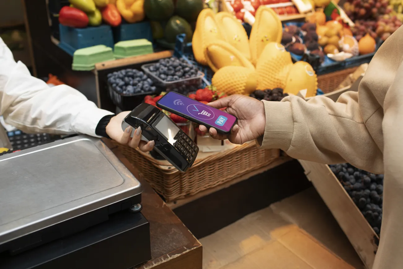 Hand paying with phone at card machine in food shop