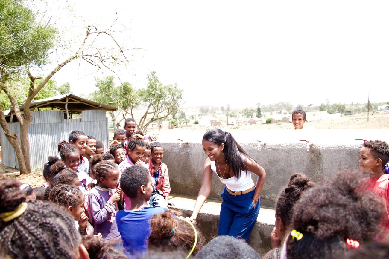 Tsion meets local school children at the opening ceremony for the pipeline extension connecting the hand pump well to Sheka Wedi Bisrat Elementary School.