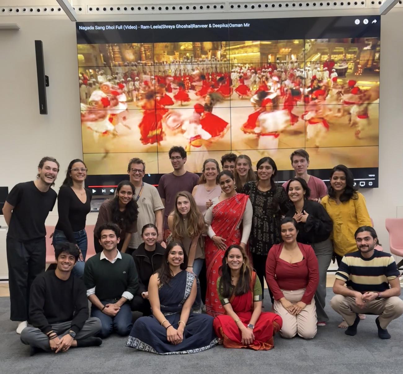 Participants of the workshop in a group with images from a Bollywood film behind them
