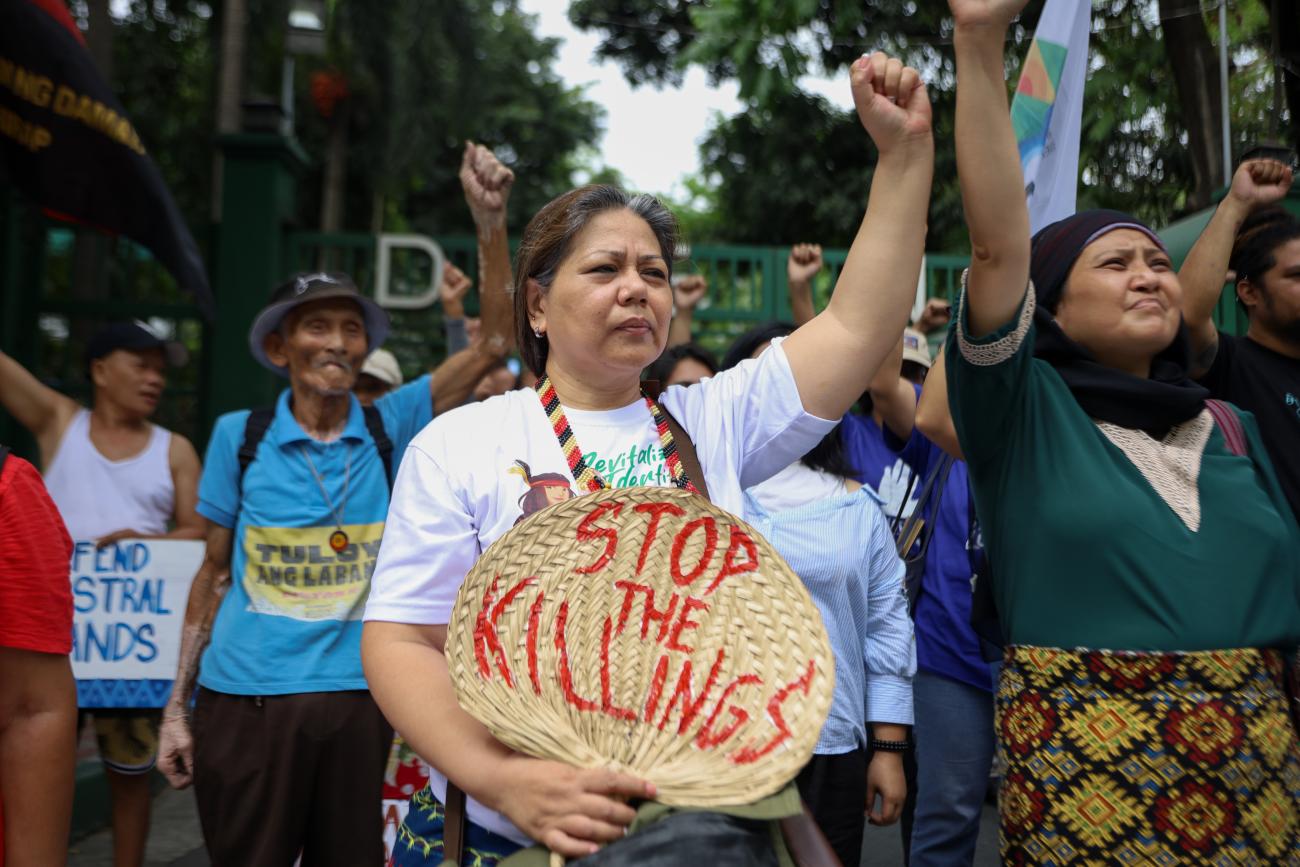 Woman environmental human rights defender holding sign with fist in the air