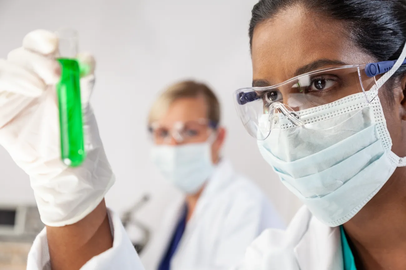 Asian Indian female scientist researcher in laboratory holding up a test tube of liquid
