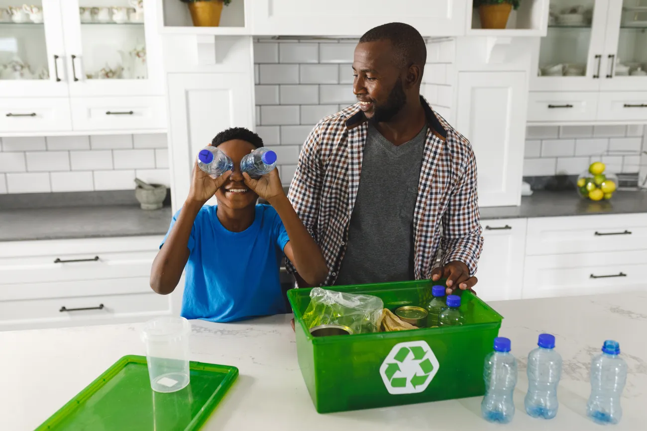 Father and son sorting recycling in kitchen, and playing with plastic bottles