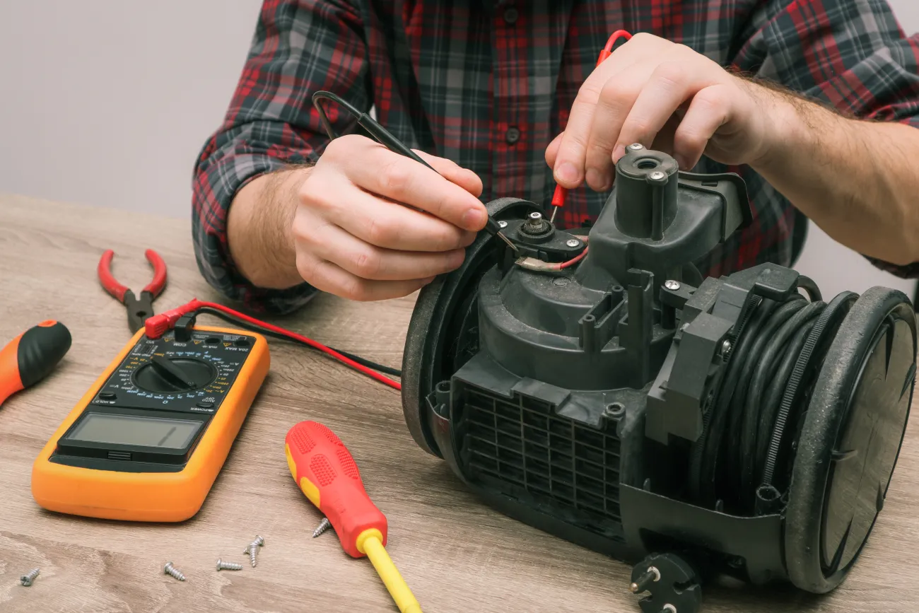 An electrical component is being repaired by a pair of hands