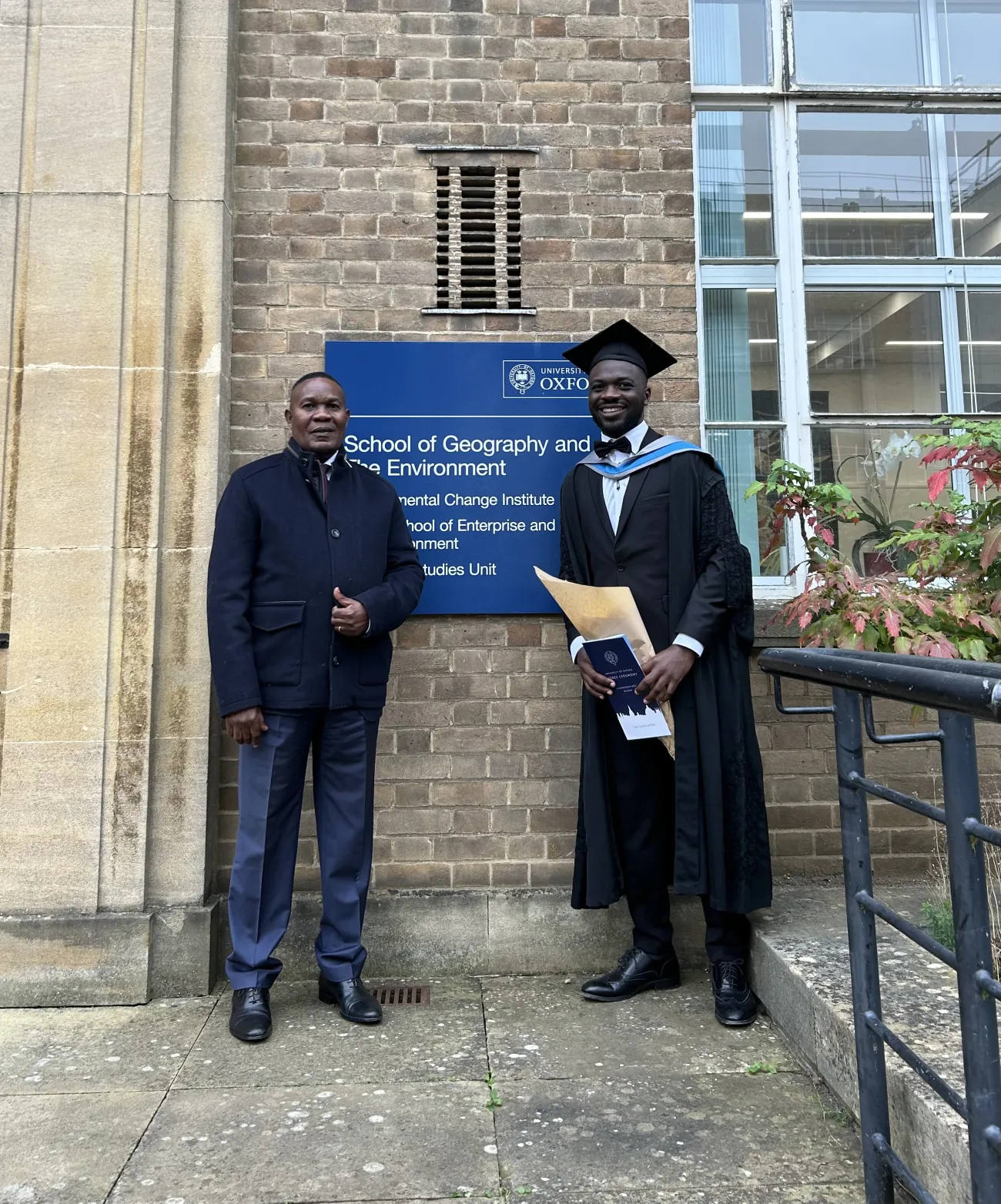 Junior with his father, Prof Mbangala, in front of the School of Geography and the Environment, University of Oxford.