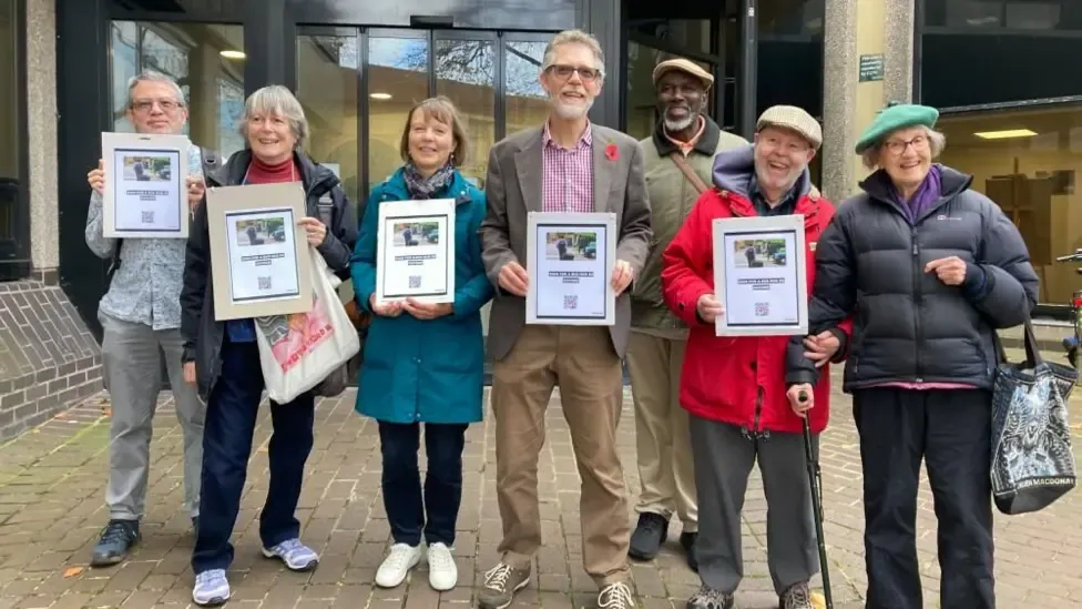 Members of Oxon4Buses in a line holding copies of their petition