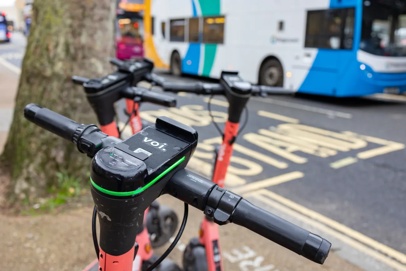 Electric scooters parked on urban street in Oxford centre with public transportation in the background