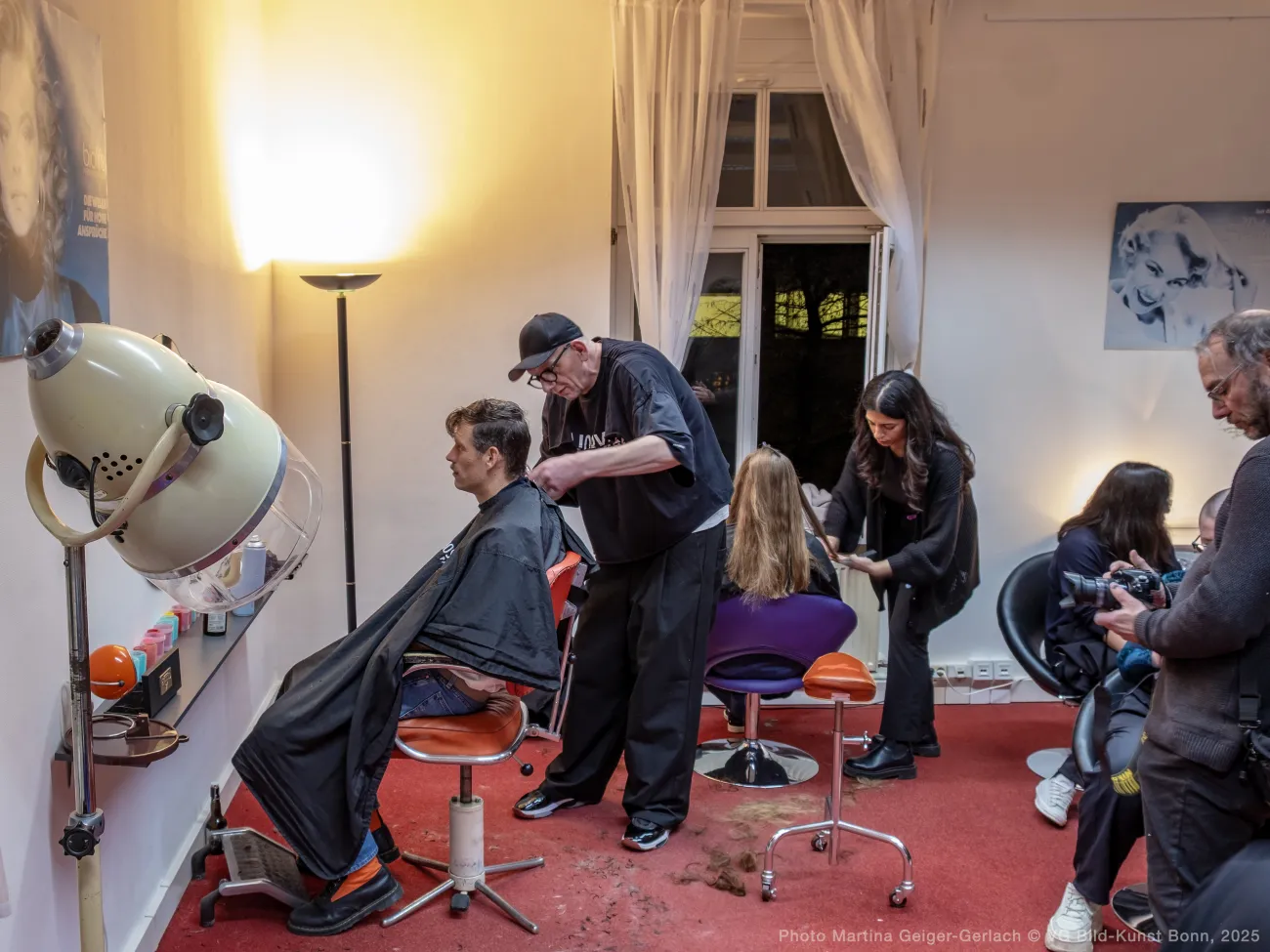 At opening event, clients 'staged' in chairs having conversations while having their hair cut