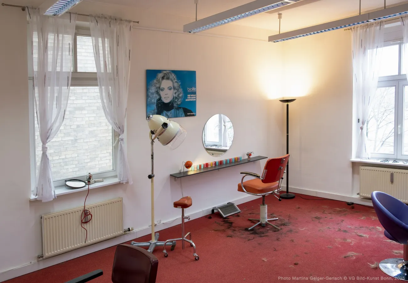 Part of the installation showing a chair at the wall with more hair cuttings on the floor