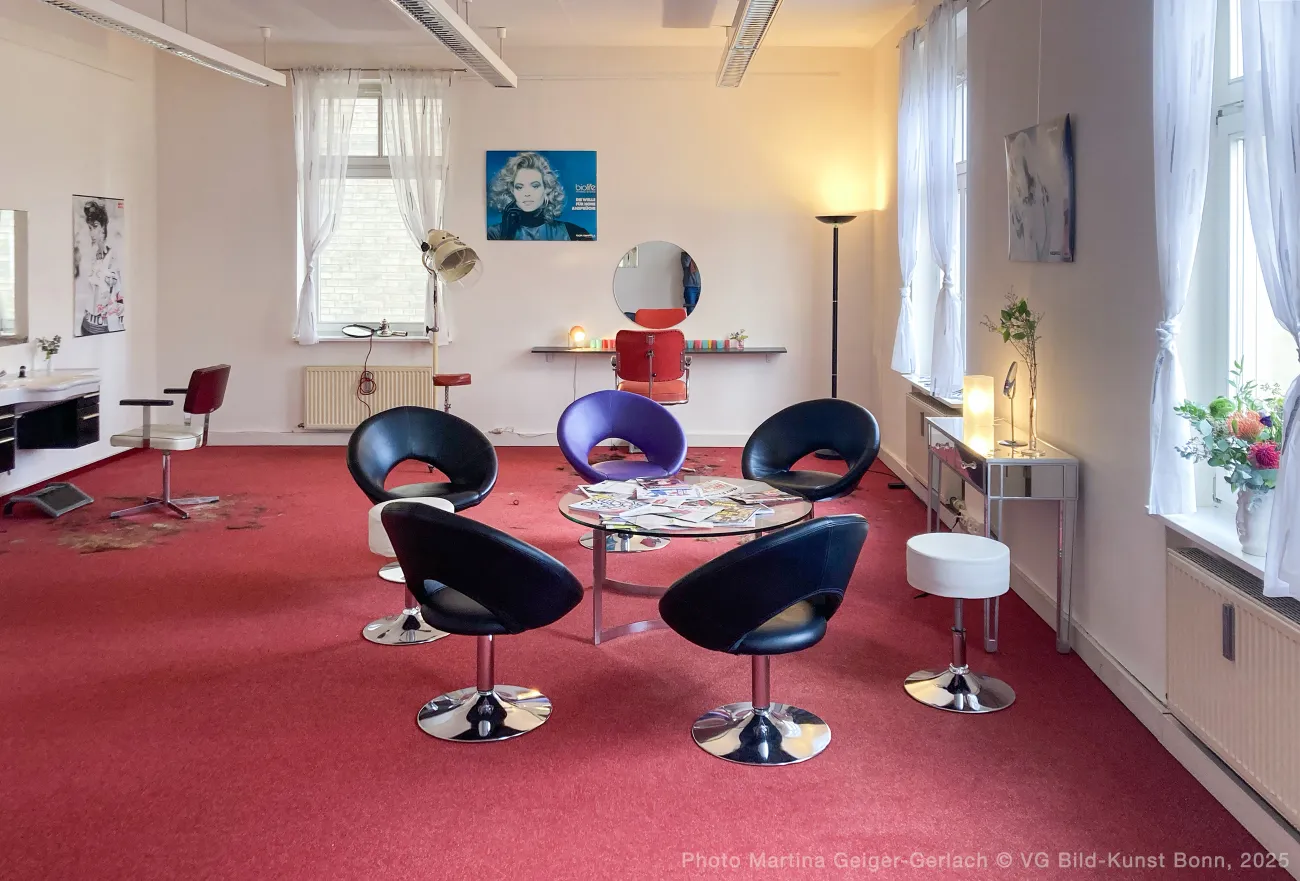 The art installation, a room set up like a salon with chairs and literature to read and hair cuttings on the floor