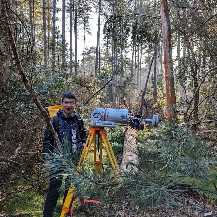 Dr Shilin Chen with a laser scanner on a tripod among the trees