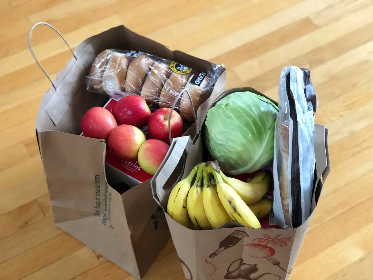 Two brown paper bags packed with fresh produce