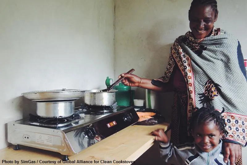 An African mum and daughter cooking together at a basic stove