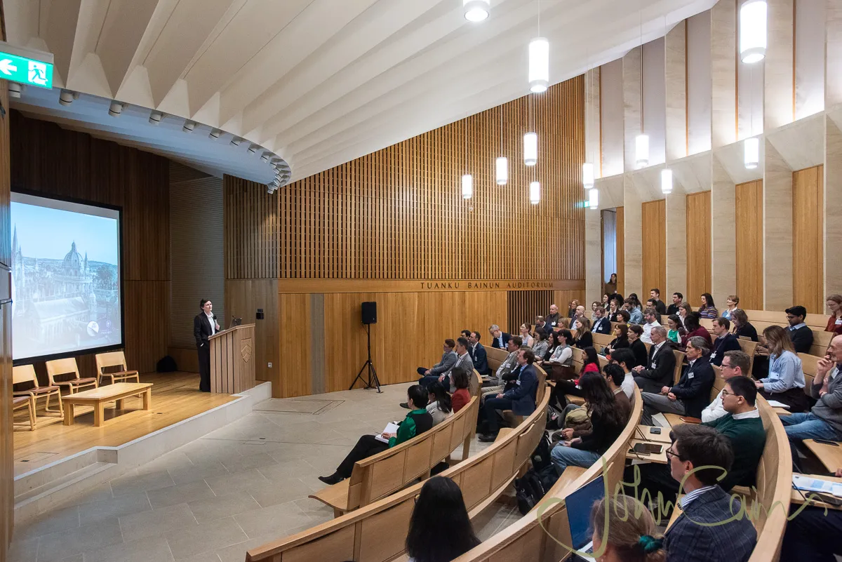 Wide shot of the lecture theatre showing the stage and lots of people in the auditorium