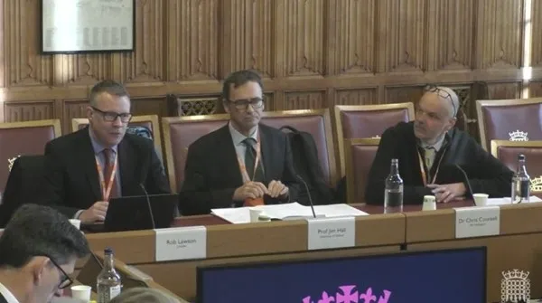 Three men in suits speaking in the House of Lords. In the middle is Professor Jim Hall