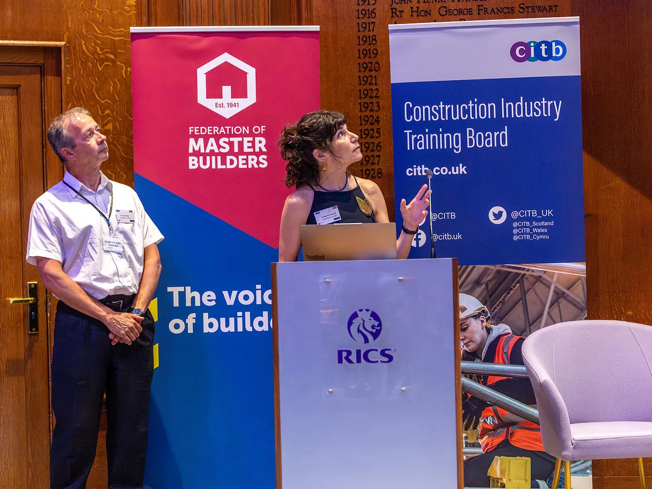Dr Marina Topouzi and Dr Gavin Killip stood in front of a podium on a stage
