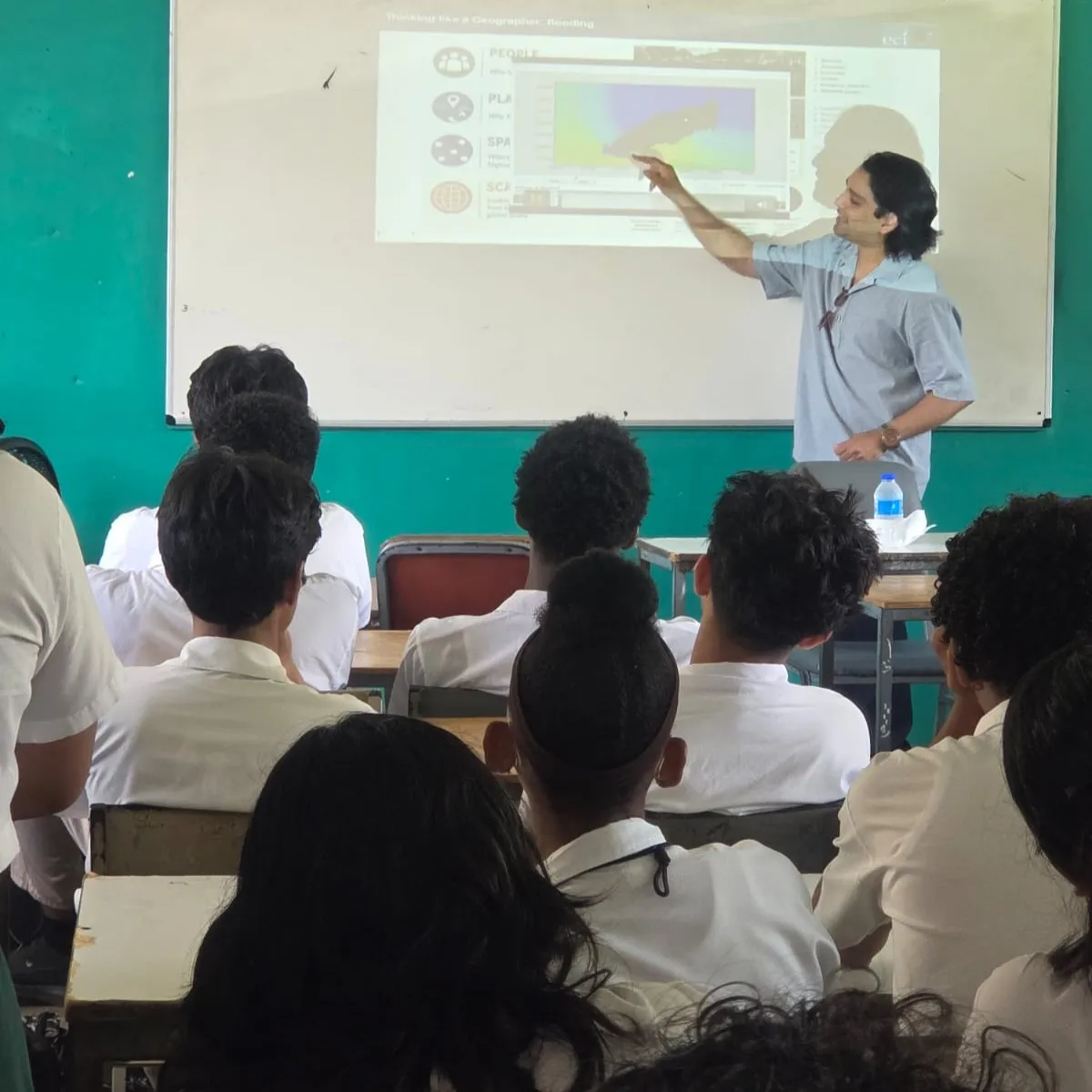 Dr Avidesh Seenath in front of a projection screen giving a talk