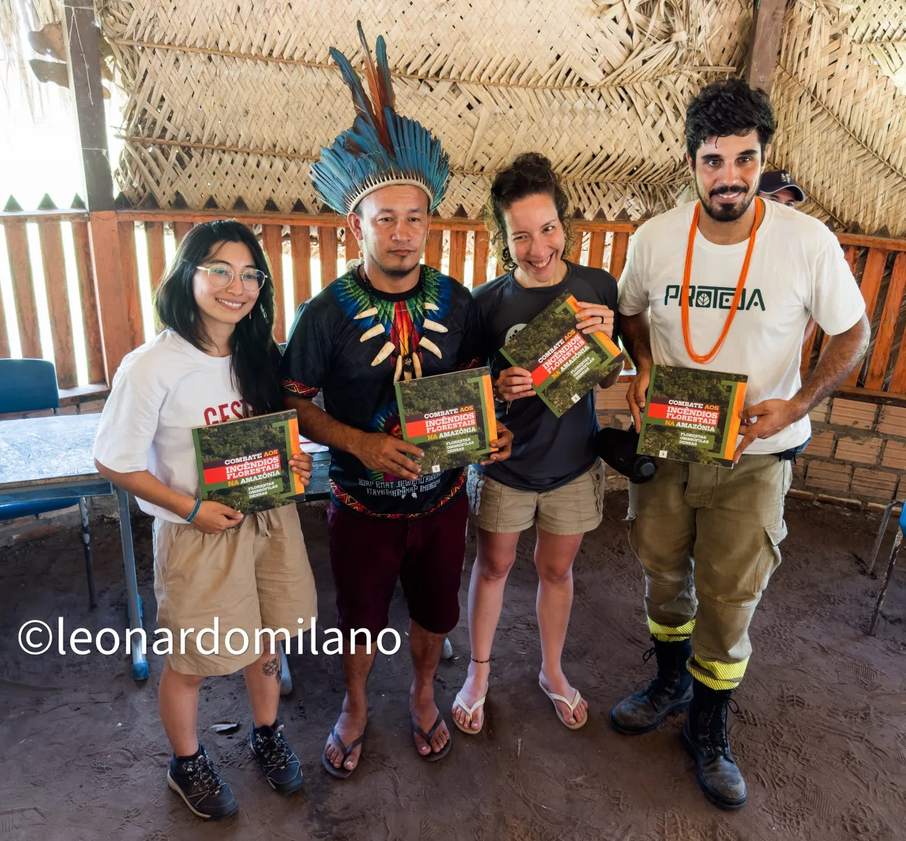 Erika standing holding book with indigenous community member and others promoting the book
