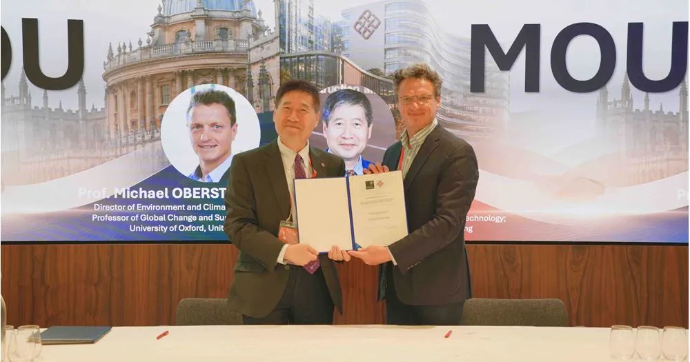 The MOU document held up after being signed by Professor Michael Obersteiner, Director of the ECI, and Professor Li Xiangdong, Dean of the Faculty of Construction and Environment at PolyU